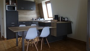 A modern kitchen with dark cabinets, a wooden table, and white chairs. - Apartment rental, sea view, Port-Louis (56), 3-star CLEVACANCES label (Port-Louis)