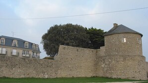 A historic stone wall with a round tower and a building with balconies. - Apartment rental, sea view, Port-Louis (56), 3-star CLEVACANCES label (Port-Louis)