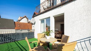 A balcony with wicker furniture, a potted plant, and a view of neighboring buildings. - Holiday studio close to the seaside beach (Rewal)