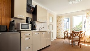 A modern kitchen with a refrigerator, microwave, coffee maker, and cabinets. There is a dining area with a table and chairs. - Holiday apartment, breakfast included (Rewal)