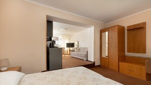 A hotel room with a bed, a wardrobe, a desk with a lamp, a television, and a view into the adjacent room. - Comfortable holiday studio, breakfast included (Rewal)