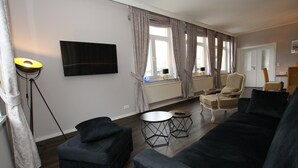 Un salon moderne avec un canapé noir, un fauteuil plus petit et une table basse ronde.