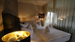 Une chambre d’hôtel avec un lit, une grande lampe sur pied et des rideaux légers.