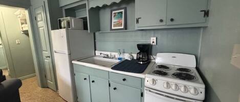 Una cocina compacta con estufa blanca, un lavamanos y armarios azul claro.
