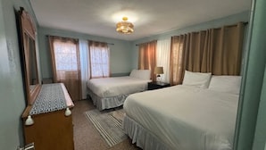 Ein Hotelzimmer mit zwei Betten, einem Nachttisch, einem Schreibtisch und einer Deckenleuchte.