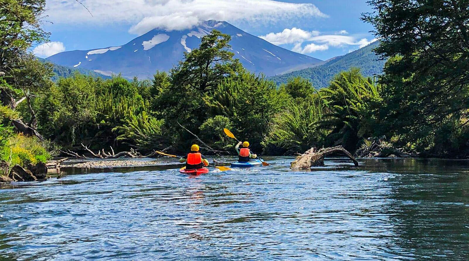 Kayakers on a river with a mountain in the background.