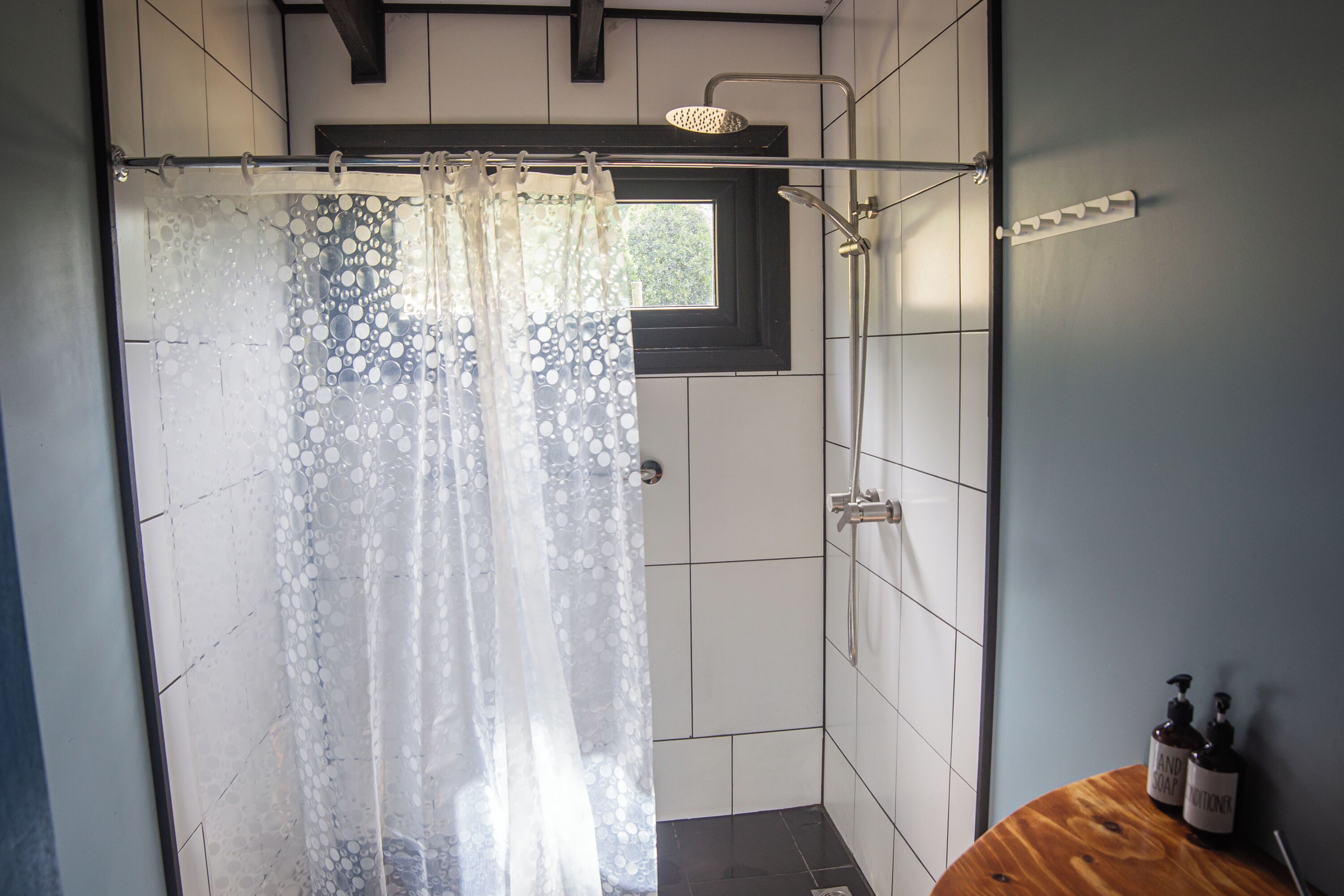 A shower area with a frosted glass door, a handheld showerhead, and a window above the shower.