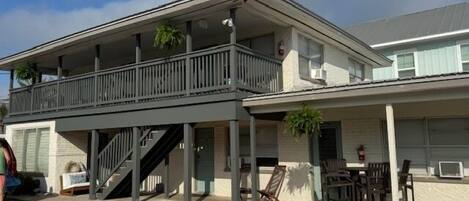 A two-story building with a balcony, outdoor seating, and a staircase leading to the upper level.