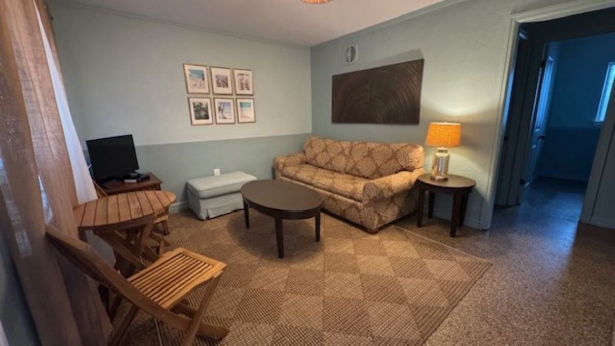 A living room with a sofa, a coffee table, a TV, and a lamp.