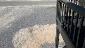 Una propiedad frente a la playa con entrada pavimentada, acceso mediante portón y vista al océano.
