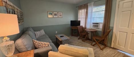 Ein Wohnzimmer mit einer Couch, einem Couchtisch, einem Fernseher und einem kleinen Tisch mit Stühlen.
