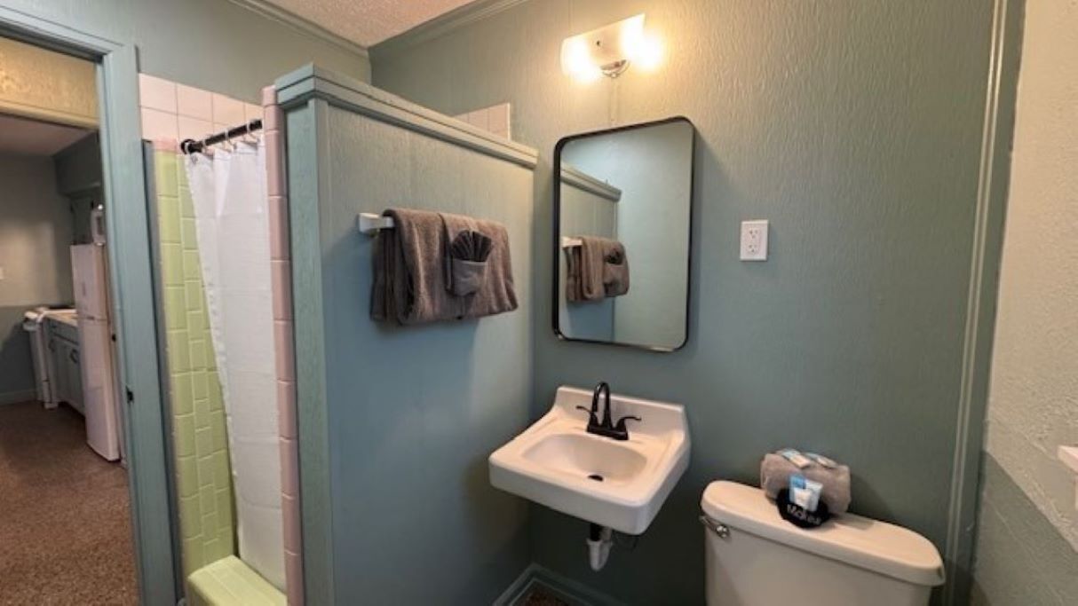 A bathroom with a sink, mirror, and toilet.