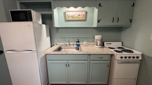 A kitchen with a refrigerator, stove, microwave, sink, and light blue cabinets.