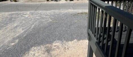 Een pand aan het strand met een verharde oprit, een poort en uitzicht op de oceaan.