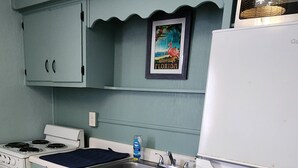 A kitchen with light blue cabinets, a white stove, a sink, and a refrigerator.