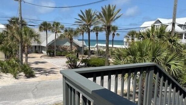 Une propriété située en bord de mer, dotée d’une terrasse en bois, de palmiers et offrant une vue sur l’océan.