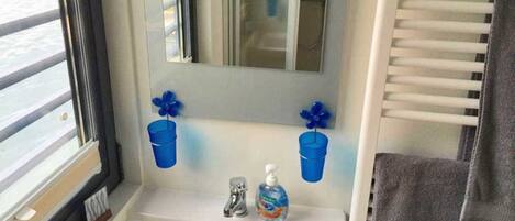 A bathroom with a white sink, two blue flower-shaped soap dispensers, a mirror, and a towel rack.