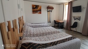 A bedroom with a bed, a desk, a chair, a TV, and a window with curtains. - Hôtel de Paris (Narbonne)