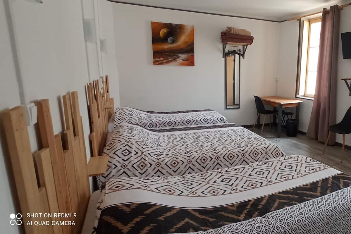 Une chambre à coucher avec un lit, un bureau, une chaise, un téléviseur et une fenêtre avec des rideaux.