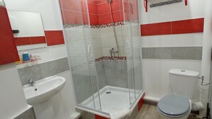 A bathroom with a glass-enclosed shower, a sink, and a toilet. - Hôtel de Paris (Narbonne)