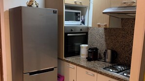 Een praktische keuken met een roestvrijstalen koelkast, een magnetron, een oven en een gasfornuis.