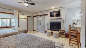 A bedroom with two beds, a fireplace, and a TV mounted above it. - Cozy ski in ski out studio in Angel Fire!  (Angel Fire)