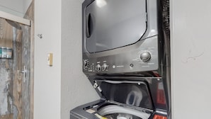 A compact washer and dryer unit with a control panel, located in a room with a partially visible wooden door and a white wall. - Cozy ski in ski out studio in Angel Fire!  (Angel Fire)