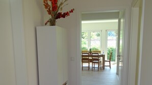 A hallway with a white refrigerator, wooden flooring, and a dining area with a table and chairs. - Sunny apartment with large garden in a local recreation area  (Postmünster)