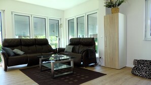A modern living room with two leather sofas, a glass coffee table, and a wooden cabinet. - Sunny apartment with large garden in a local recreation area  (Postmünster)