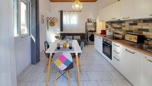 A compact kitchen with a dining area, wooden ceiling, and a hanging light fixture.