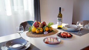 A dining table set with plates, a bottle of wine, and a fruit arrangement.