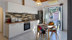 A modern kitchen with white cabinets, a tiled backsplash, and a dining area with a table set for two.