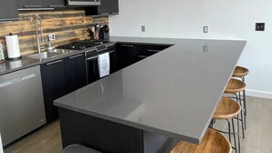A modern kitchen with a large island, dark cabinetry, a microwave, and a stainless steel sink. - Stay at the historic Opera House in downtown Salida! (Salida)