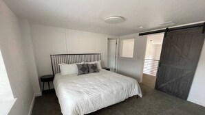 A bedroom with a large bed, a small bedside table, a wardrobe, and a sliding door to a balcony. - Stay at the historic Opera House in downtown Salida! (Salida)