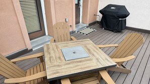 A wooden deck with a table and chairs, a covered grill, and a door with a window. - Stay at the historic Opera House in downtown Salida! (Salida)