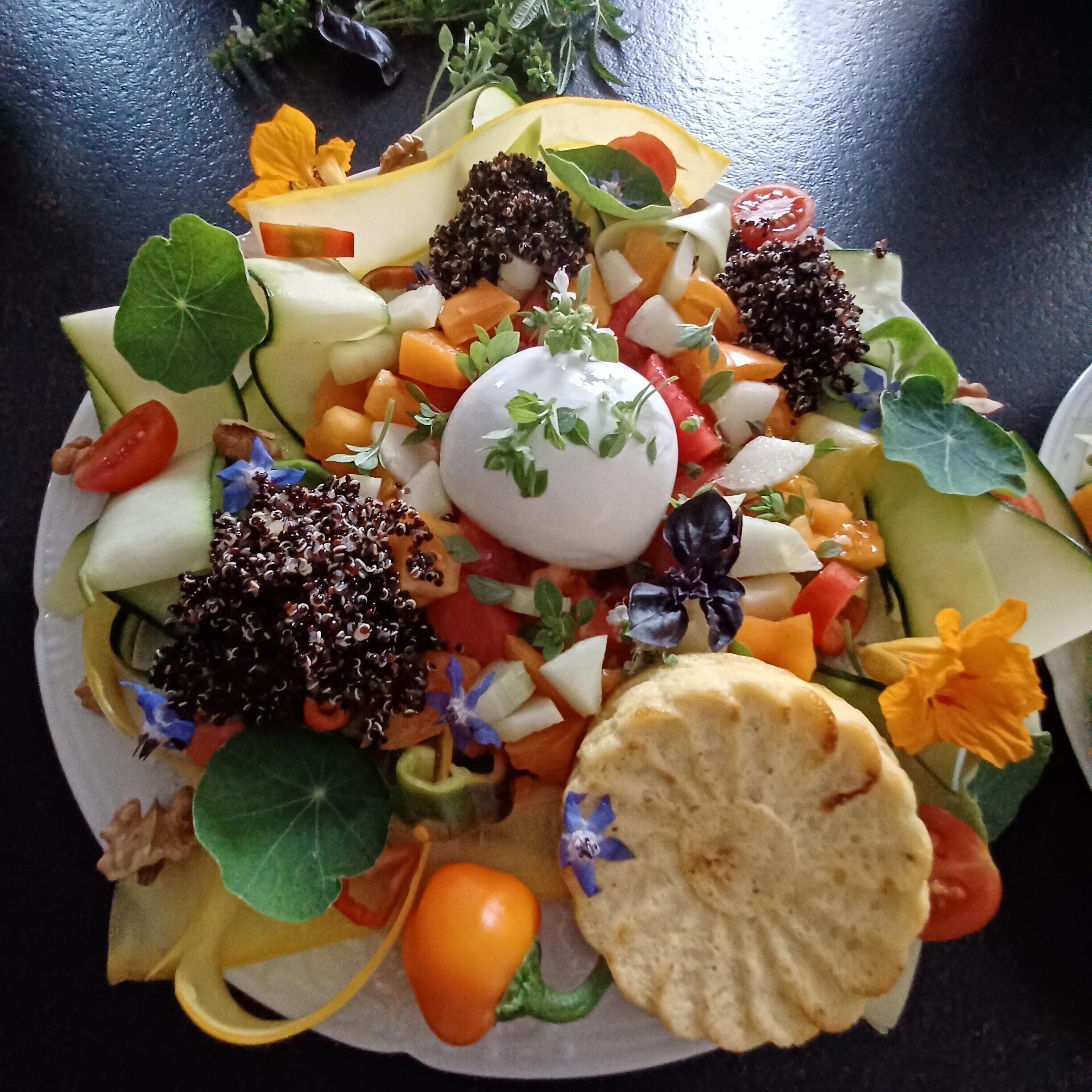 Ensalada con diversos vegetales y una cucharada de crema en el centro.