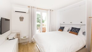 Une chambre à coucher avec un lit, une télévision, une petite table et une fenêtre avec des rideaux.
