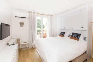 A bedroom with a bed, a TV, a small table, and a window with curtains. - L'Escapade Nature et Gourmande, Chambres d'Hote avec Piscine (Pujaudran)