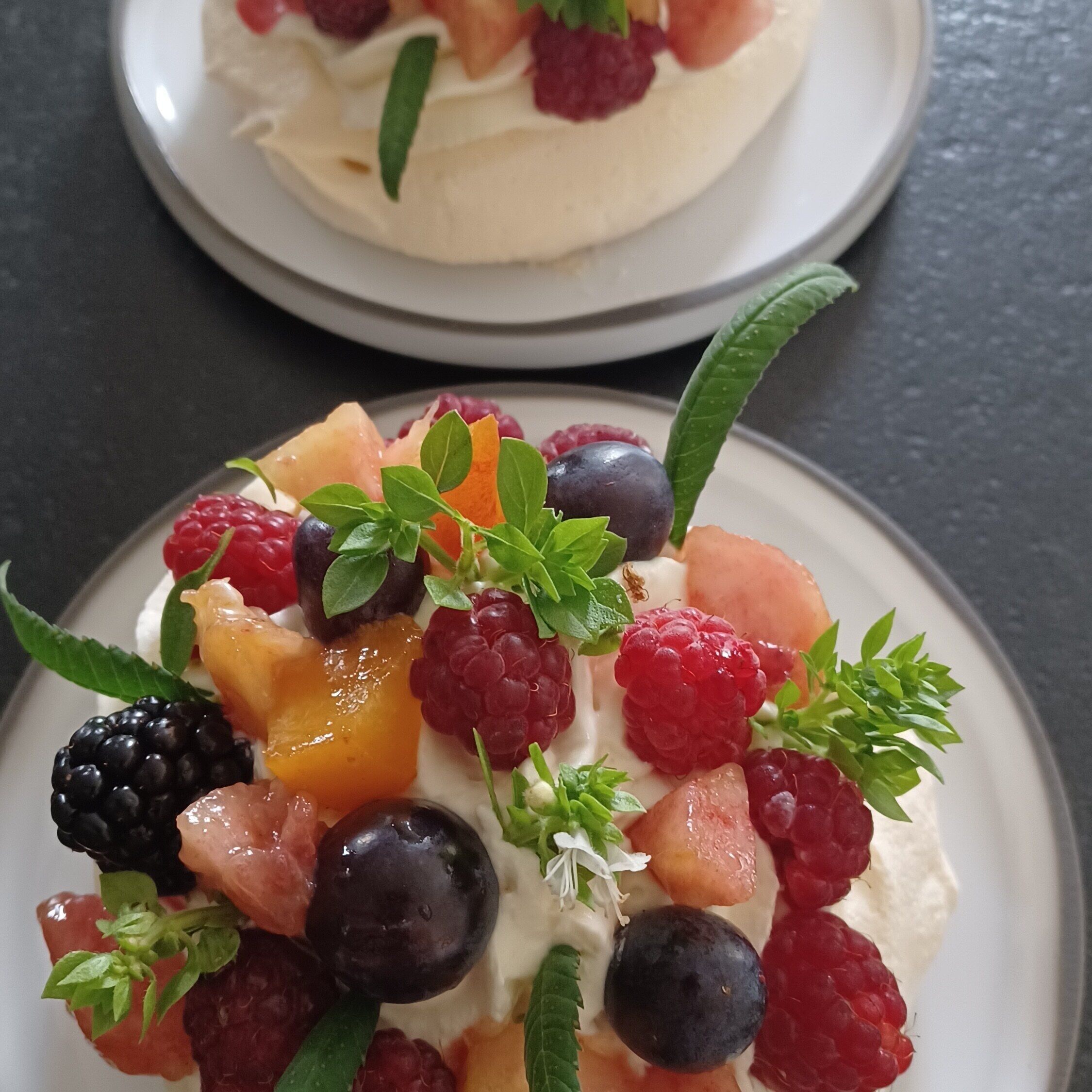 A dessert with various fruits and cream on a plate.
