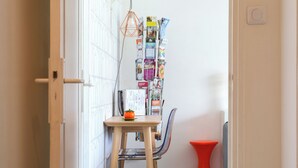 A narrow hallway with a wooden table and chair, a red stool, and a wall-mounted magazine rack. - Maison deco années 70 / 5 p. garden south Tours (Joué-lès-Tours)