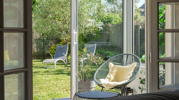 A room with a large glass door leading to a garden with a chair and a potted plant. - Maison deco années 70 / 5 p. garden south Tours (Joué-lès-Tours)