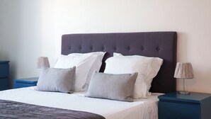 A neatly made bed with white and gray pillows, a dark headboard, and a blue nightstand with a lamp. - Maison deco années 70 / 5 p. garden south Tours (Joué-lès-Tours)