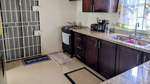 A compact kitchen with dark wooden cabinets, a gas stove, a coffee maker, and a sink. - Awesome Sea View, and Pool, Gym, and Tennis Court Access! (Florence Hall Village)