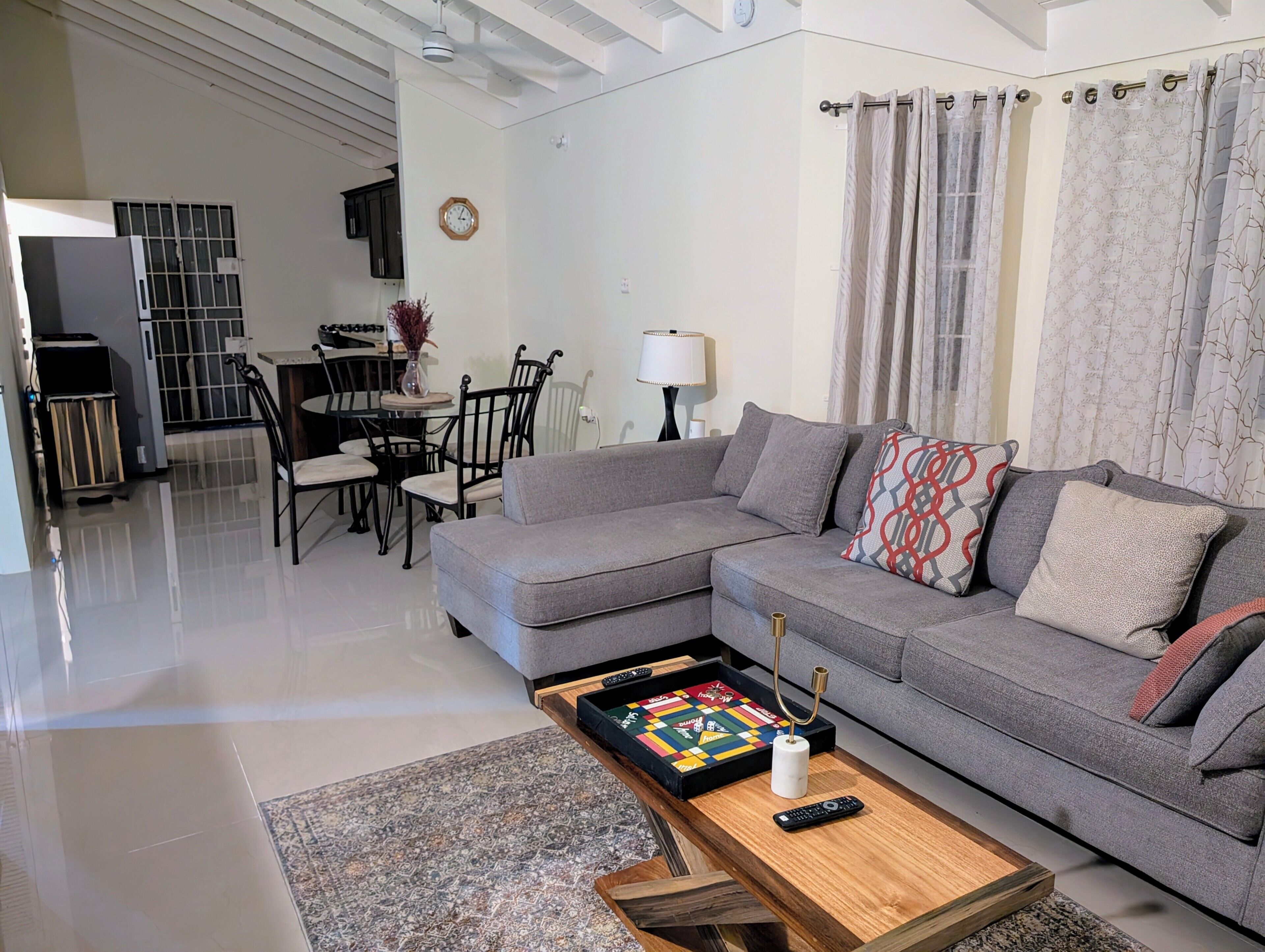 Ein modernes Wohnzimmer mit einem grauen Sofa, einem Couchtisch und einem Essbereich mit Tisch und Stühlen.