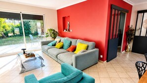 A modern living room with a grey sofa, teal armchair, and a red accent wall.