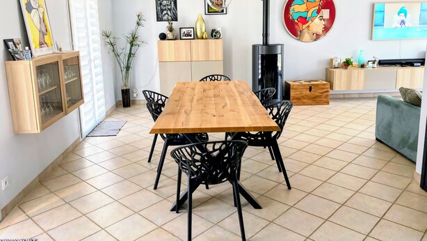 Een moderne woonkamer met een houten eettafel, zwarte stoelen, een televisie en een open haard.