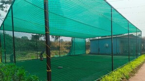 A greenhouse with a green net roof, surrounded by plants. - RASS Resort (Karjat)