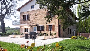 A two-story stone house with a balcony, outdoor seating, and a garden.