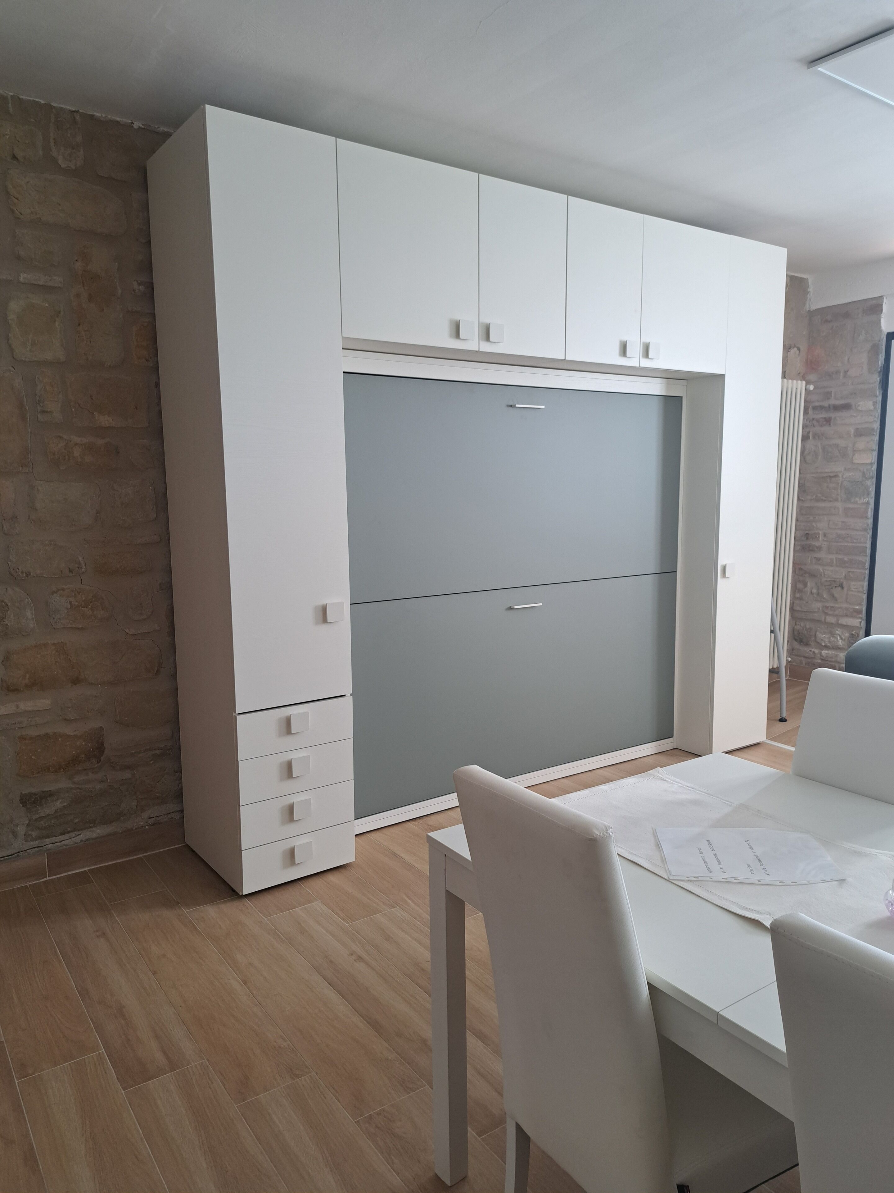 A modern room with a built-in wardrobe, a dining table, and chairs.