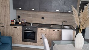 A modern kitchen with dark cabinets, a stainless steel sink, and a dining area with a white table and chairs.